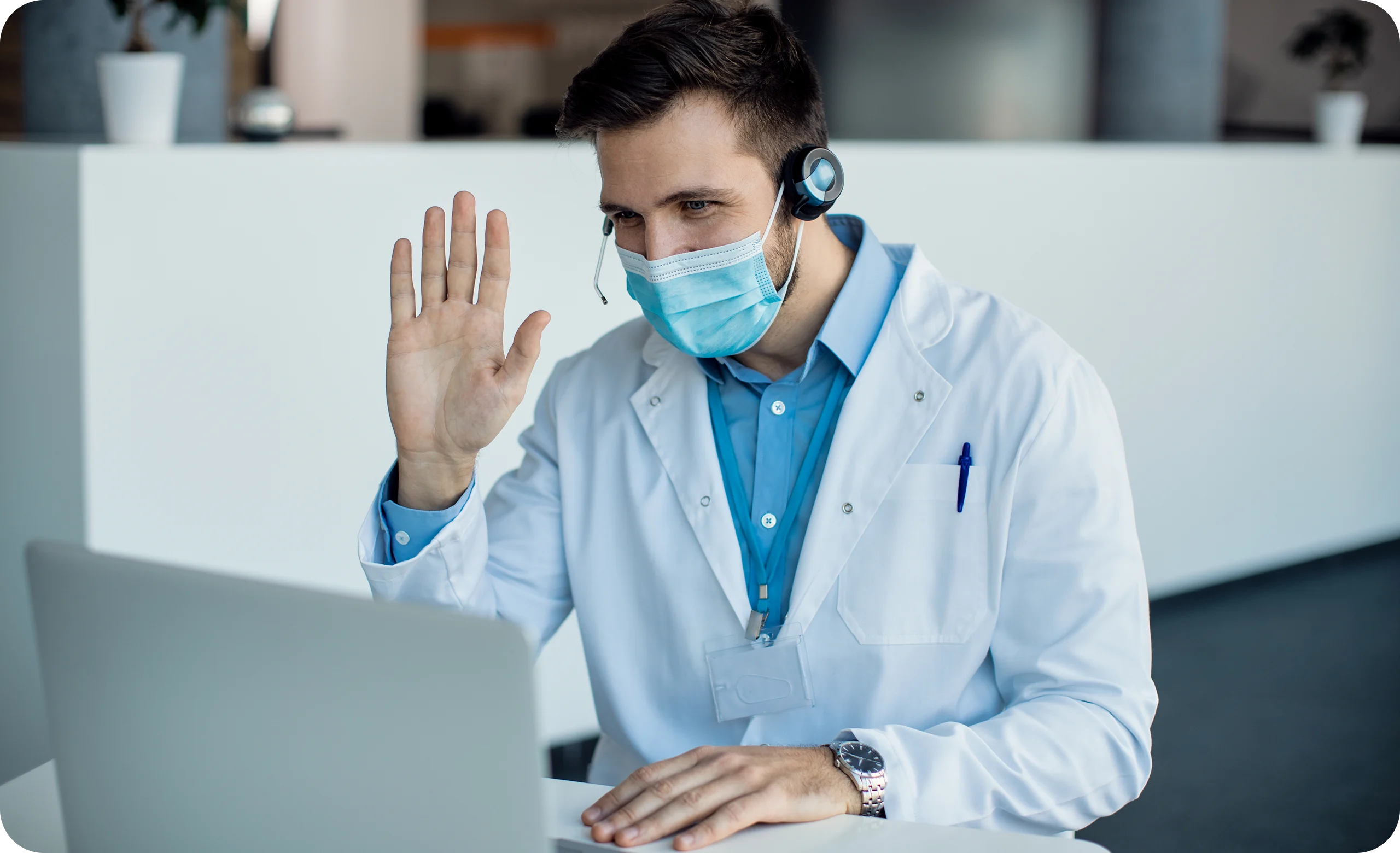 Doctor wearing headset and mask conducting virtual telemedicine consultation with patient on laptop